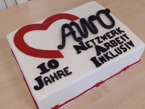 Eine Tort mit der Zuckerguss Aufschrift: "10 Jahren AWO Netzwerk Arbeit Inklusiv" steht auf einem Tisch
