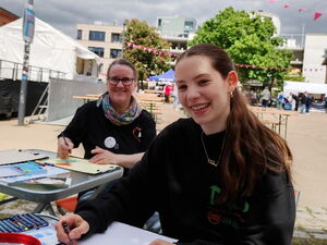 2 Frauen sitzen lächelnd an zwei Klapptischen und malen / zeichnen.